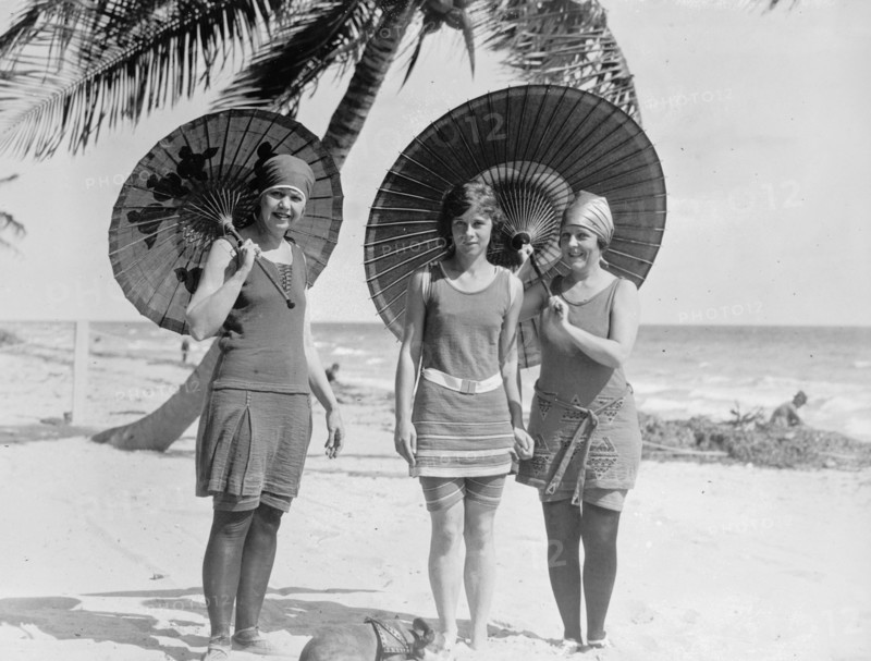 Three women on a beach with umbrellas in the early 20th century ca.  between 1910 and 1920