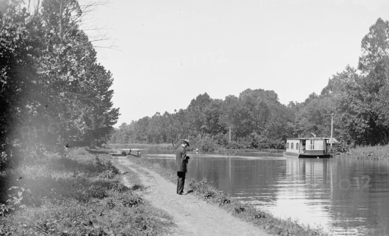 Man standing next to the C&O Canal, possibly taking a photo of a boat / Chesapeake & Ohio Canal ca. between 1909 and 1923