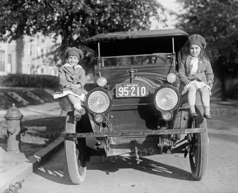 Children sitting on the fender of a car next to a fire hydrant ca.  between 1918 and 1920