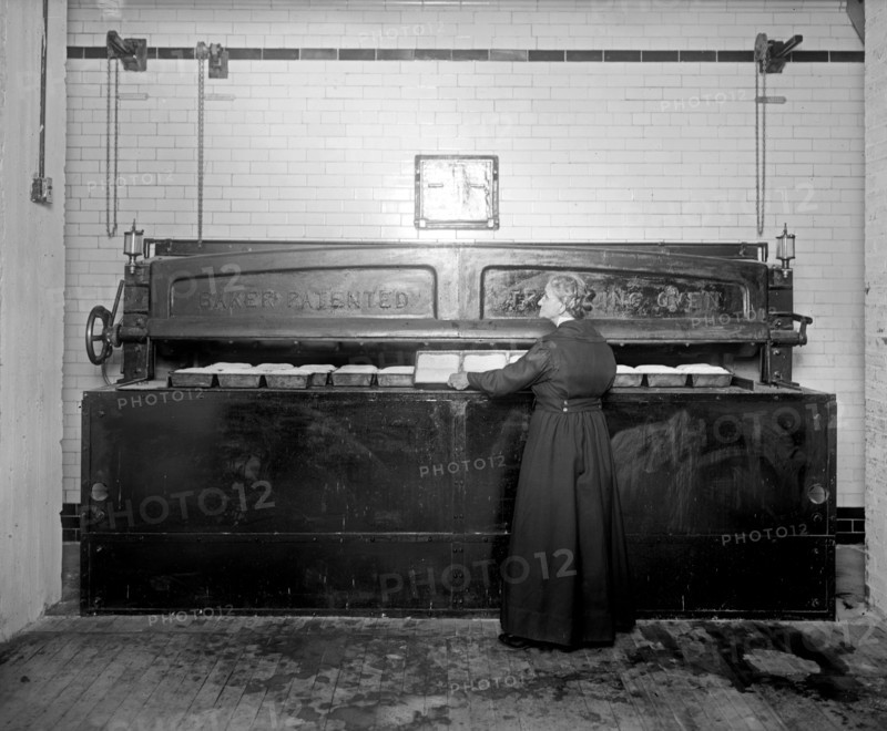 Woman baking, using a commercial oven at the Caking Baking Company group ca.  between 1918 and 1928