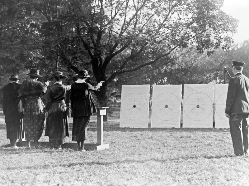 Four policewomen shooting at targets, as a policeman watches ca. 1909