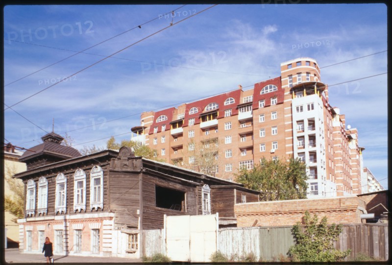 Log house, Marshal Zhukov Street #95 (around 1900), foreground, and in the background is a typical modern apartment building of the post Soviet period (late 1990s), Omsk, Russia 1999.
