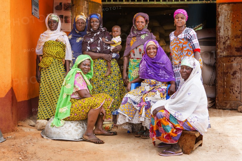 These West African women wearing traditional colorful dress pose for the camera in their village ca. 21 February 2018