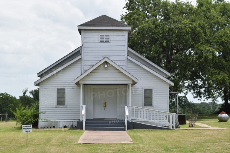 Old white church building NE of Brenham, TX, pastor parking only sign in lower left side of image