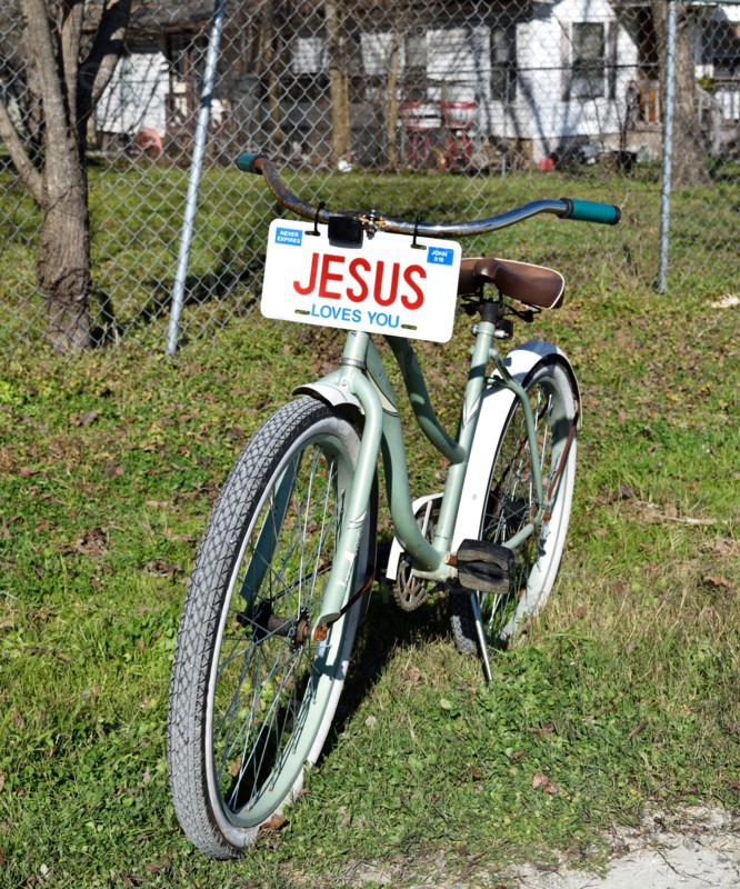 A bicycle with a JESUS license plate sitting in the front yard of a home in a small Texas town