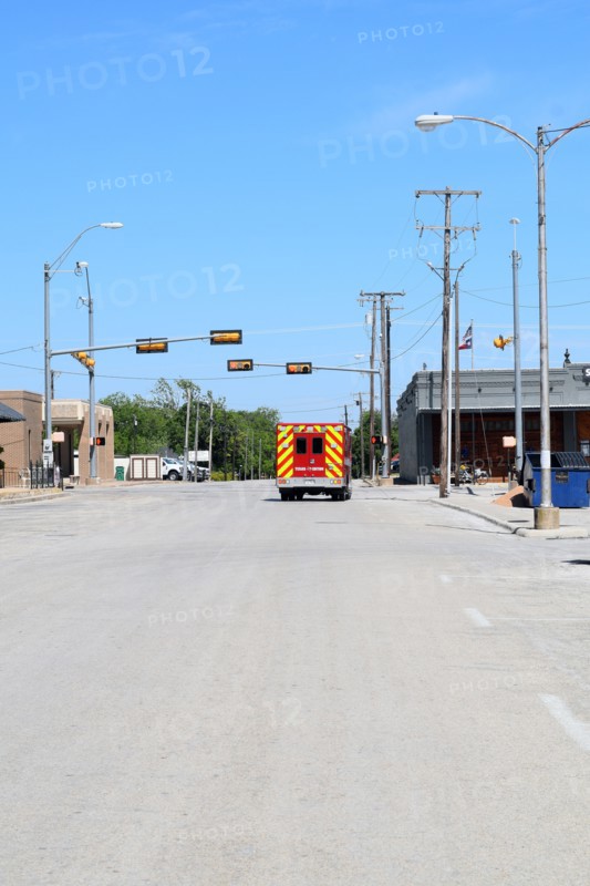 An ambulance stopped at a red traffic light in Commanche, TX