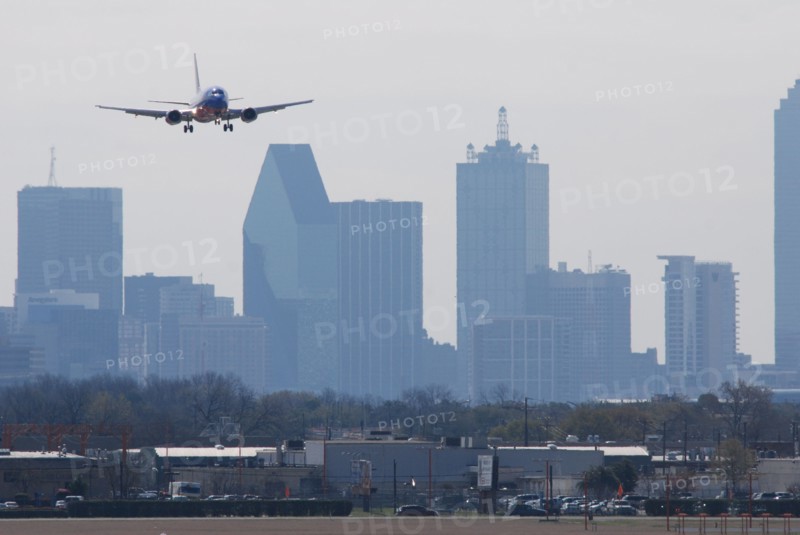 A Southwest Airlines plane landing at Love Field in Dallas, TX; Downtown Dallas in the background (ca. 2010, note the old color scheme)