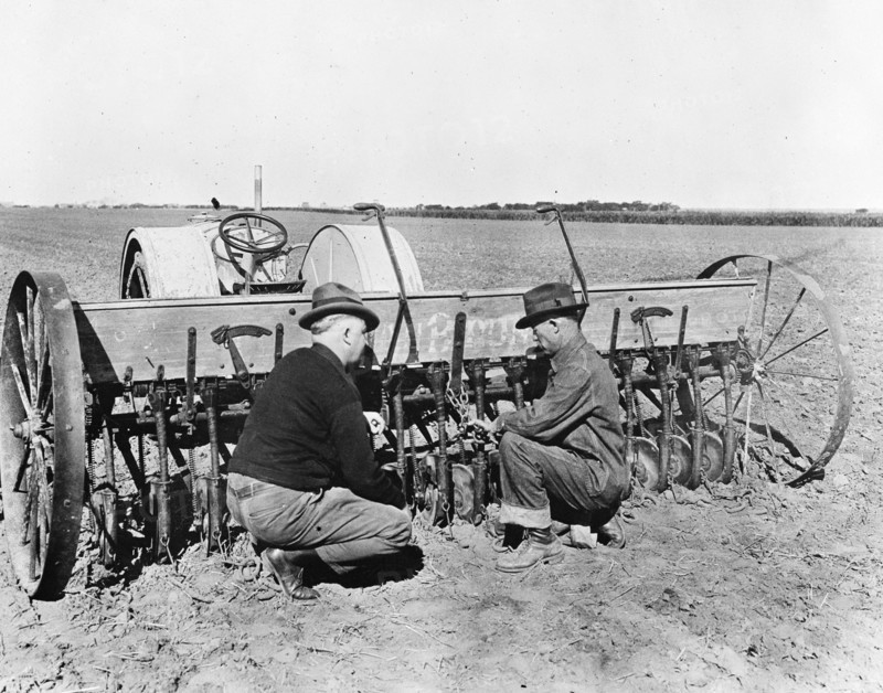 County agent inspecting farmer's wheat seeder