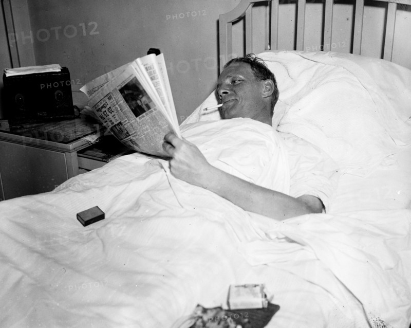 Man in hospital bed smoking a cigarette
