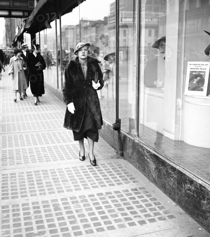 Woman walking down sidewalk in city