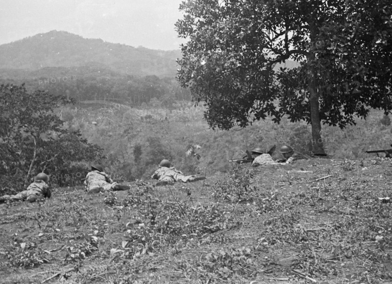 Soldiers lie on the ground in position and overlook a valley in Bandung, Indonesia, Dutch East Indies ca. 1946