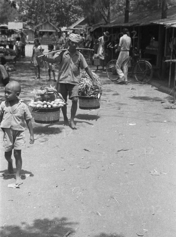 Vegetable seller with baskets on yoke; Date 1947; Location Indonesia, Dutch East Indies