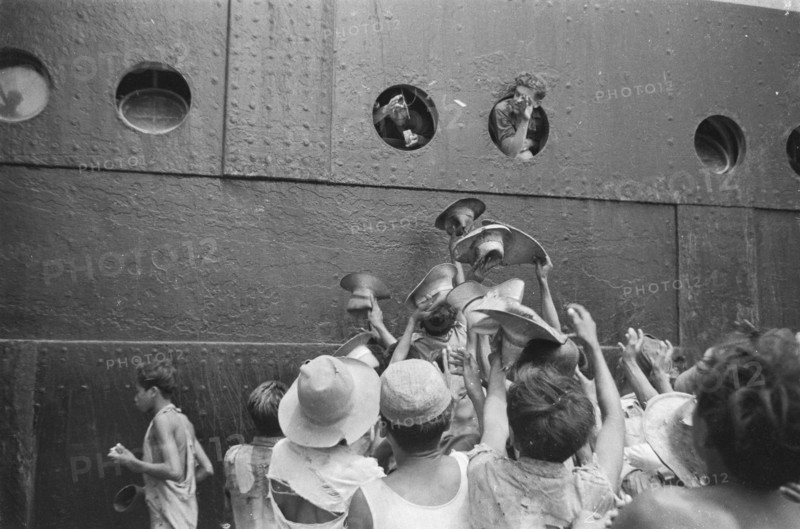Soldiers throw cigarettes from the portholes for the children on the quay in Jakarta Indonesia ca. 1946