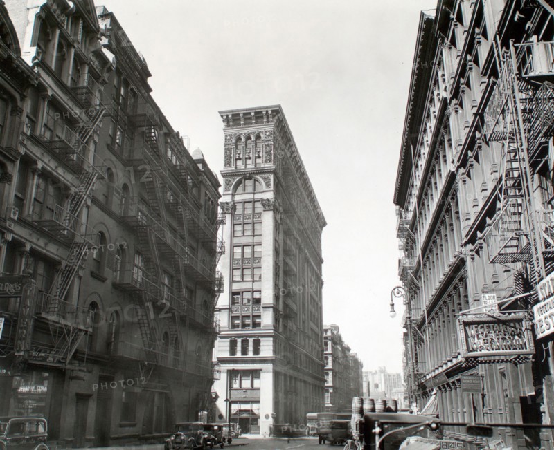 1930s New York City - Looking down Broadway, ornate Bank of Sicily Trust near center of image, sign for vegetarian restaurant, right, cars and trucks, Broadway near Broome Street, Manhattan ca. 1935
