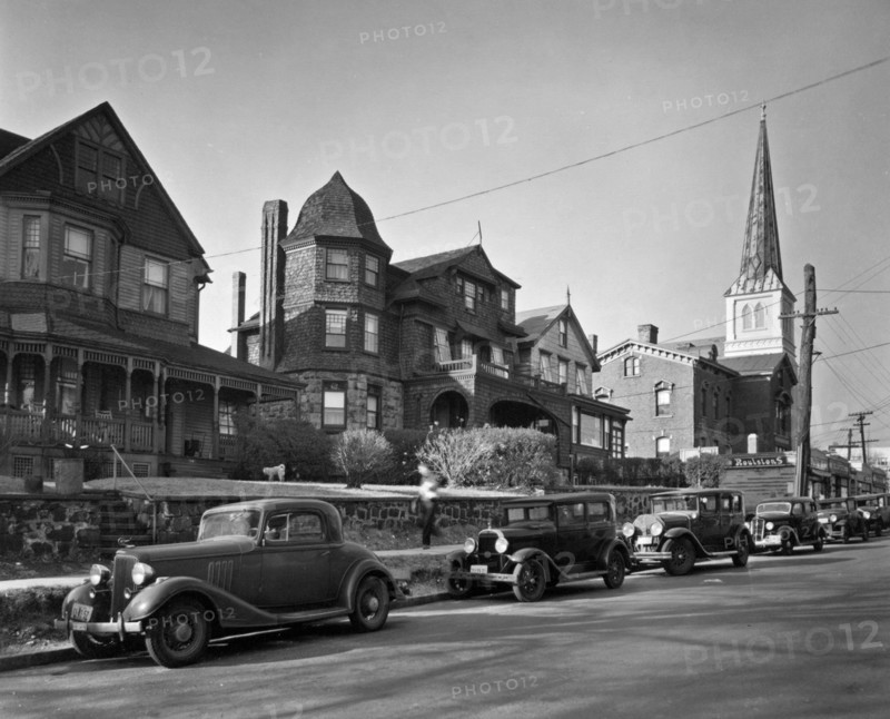 Looking up street, Queen Anne house at left, church, businesses at right, Shingle style and another house in middle, cars along the street. St. Mark's Place, no. 340-348, Staten Island ca. 1937