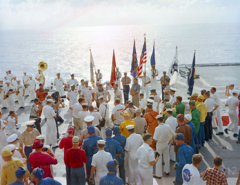 (21 July 1966) The crew of the Gemini-10 spaceflight, astronaut John W. Young (left), command pilot, and Michael Collins, pilot, talk on live radio and television during welcome aboard ceremonies on the deck of the USS Guadalcanal.