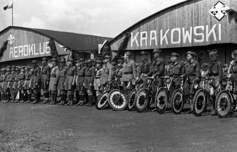 Cyclists with decorated bikes in front of the hangar of the Krakow Aeroclub at the Rakowicki airport ca. May 1, 1937