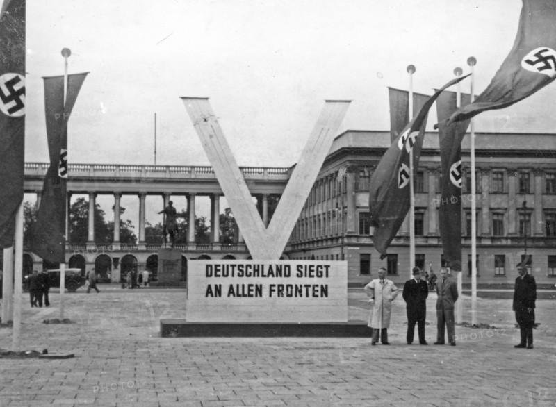 Deutschland siegt an allen Fronten” („Germany wins on all fronts”) and "V" sign standing in front of gubernatorial residence of Hans Hans Fischer in Saxon Palace on Pilsudski Square ca. 1940