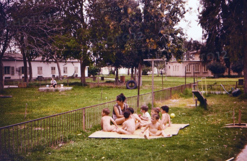 Israel April 1965:  Toddlers enjoying the fresh air, wearing no clothes, with a woman caretaker on an Israeli Kibbutz