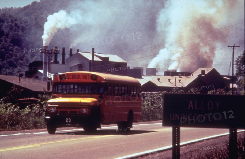 1970s - school bus driving down road in front of polluting factory (possibly Alloy, West Virginia)