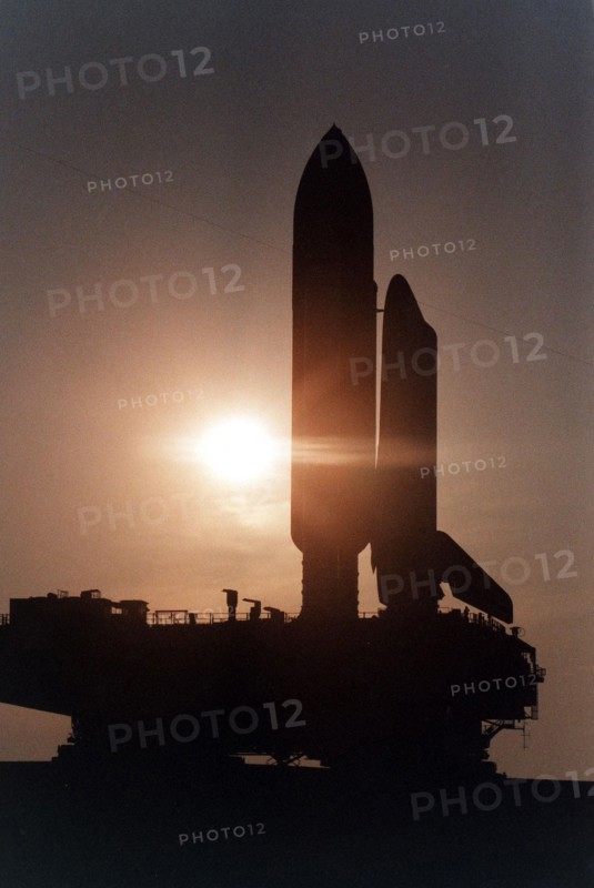 Cast in silhouette by the rising sun, the Space Shuttle Atlantis slowly and carefully makes the journey along the Crawlerway between the Vehicle Assembly Building and Launch Pad 39A ca. 1997