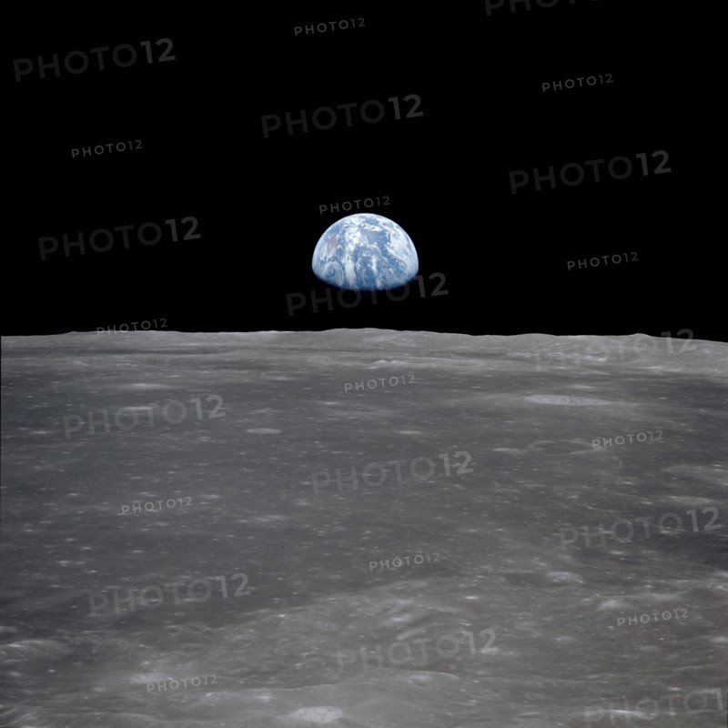 (July 1969) --- This view from the Apollo 11 spacecraft shows the Earth rising above the moon's horizon. The lunar terrain pictured is in the area of Smyth's Sea on the nearside