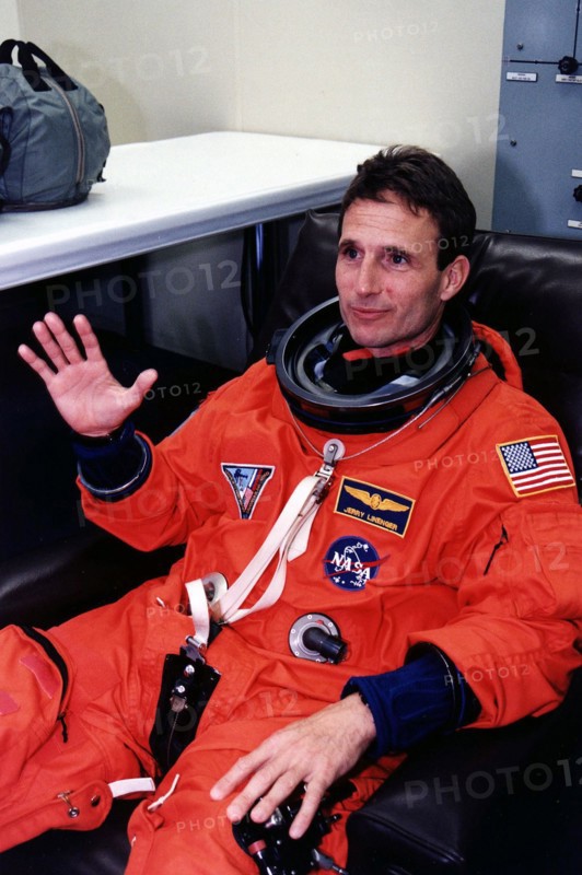 1997 - STS-81 Mission Specialist Jerry Linenger waves to the camera in his launch/entry suit and helmet in the suitup room of the Operations and Checkout (O&C) Building.