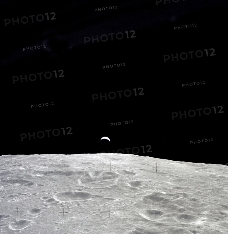 Earth rises above the lunar horizon as seen from Apollo 12 in lunar orbit