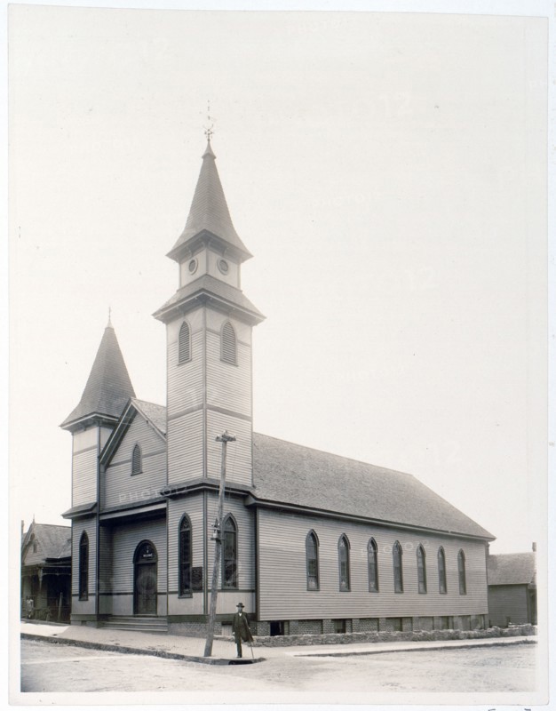 African American man standing on sidewalk in front of church c. 1900