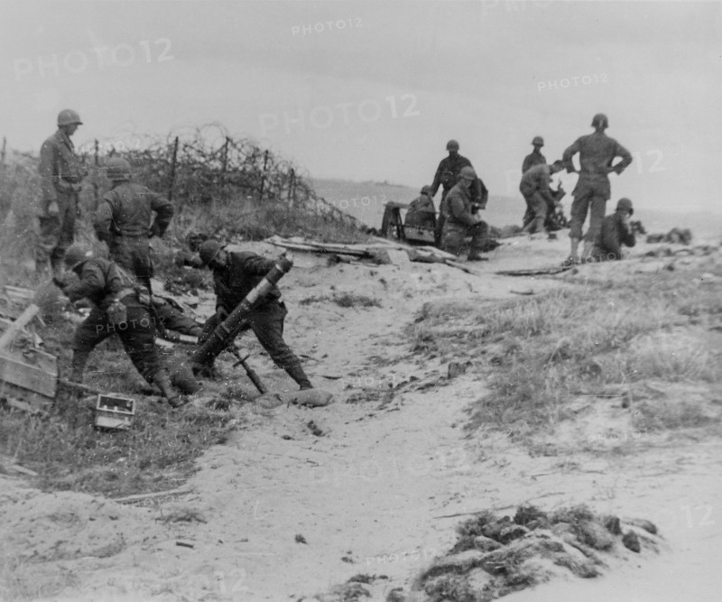 A mortar crew stands back just before firing into a Nazi position somewhere along the Normandy Coast, France.