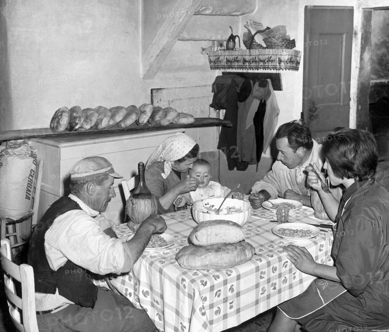 famille à table à l'arrière de la boulangerie, miches de pain toscan sur la table, 1967
