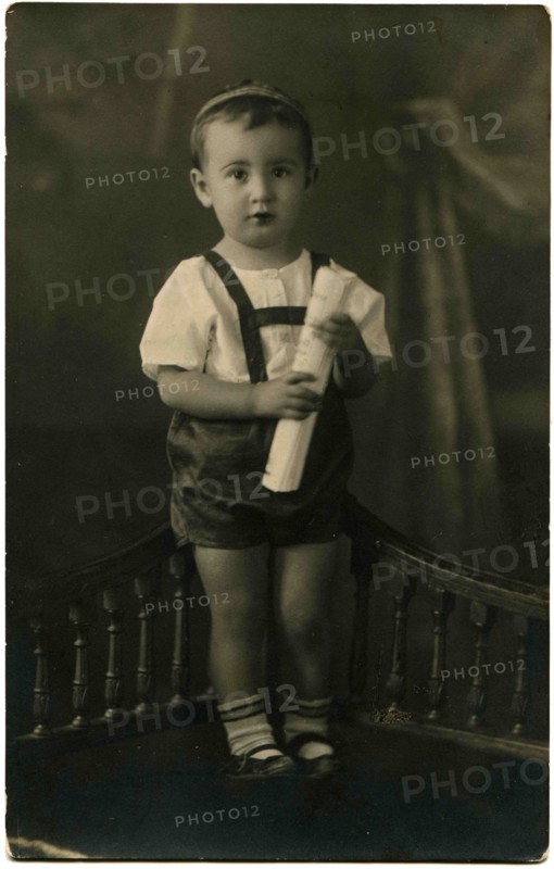 The little boy in shorts standing on a bench.