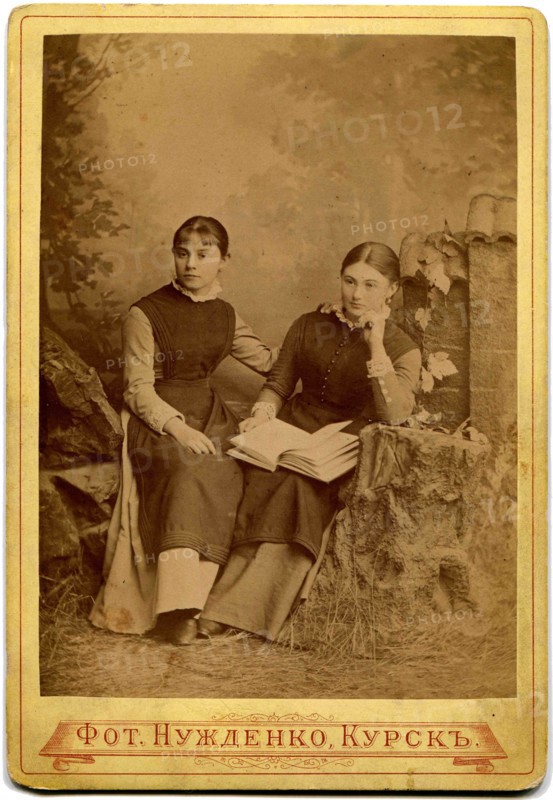 Two girls with a book in her lap.
