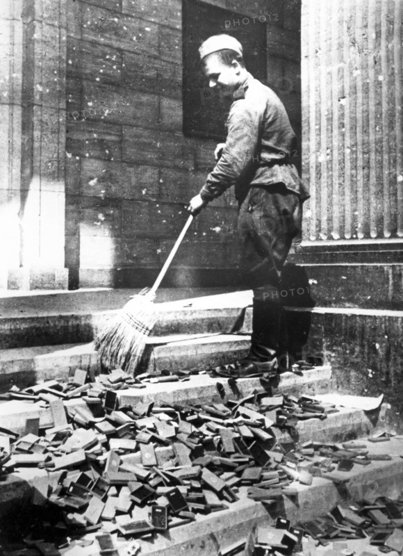 Russian Soldier Cleans Nazi Propaganda Material.