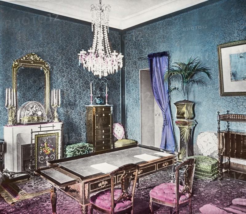 A Victorian room, fire screen and table with chairs and furniture.
