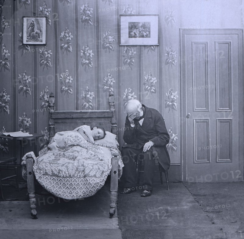 Jessica lies ill on bed with a vicar sitting next to her.