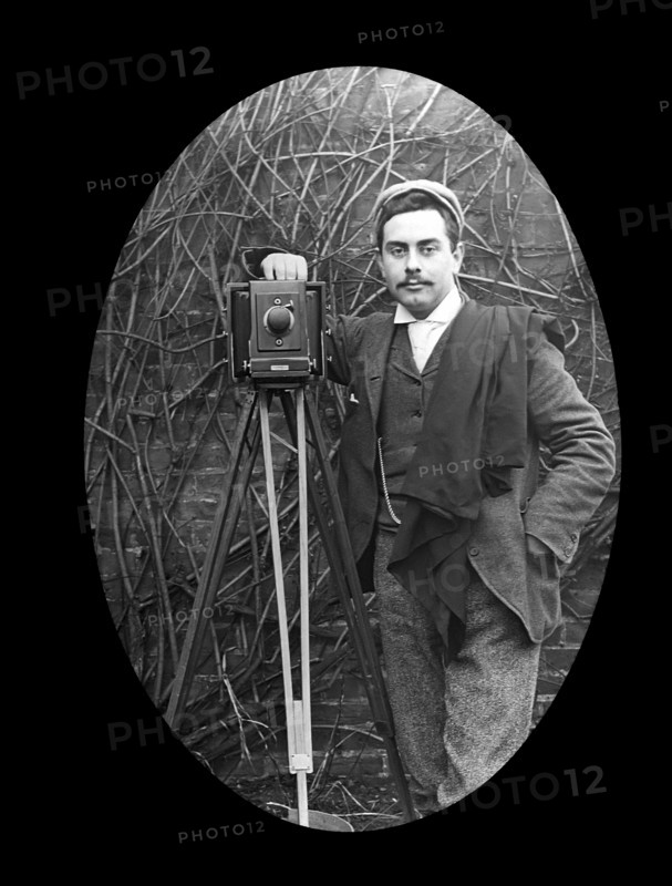 A photographer and tripod posing for a photograph in 1897.