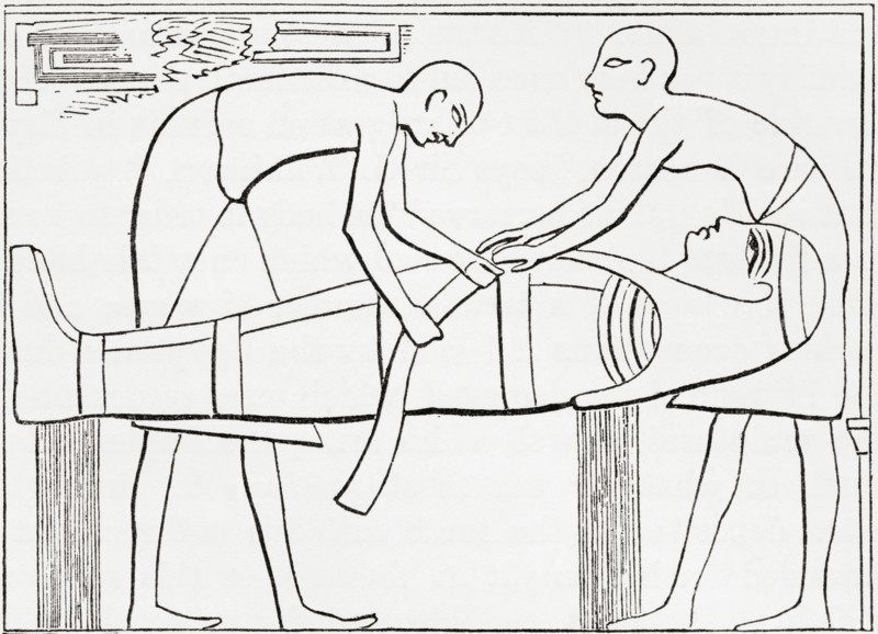 Ancient Egyptians swathing or wrapping bandages round a mummy.