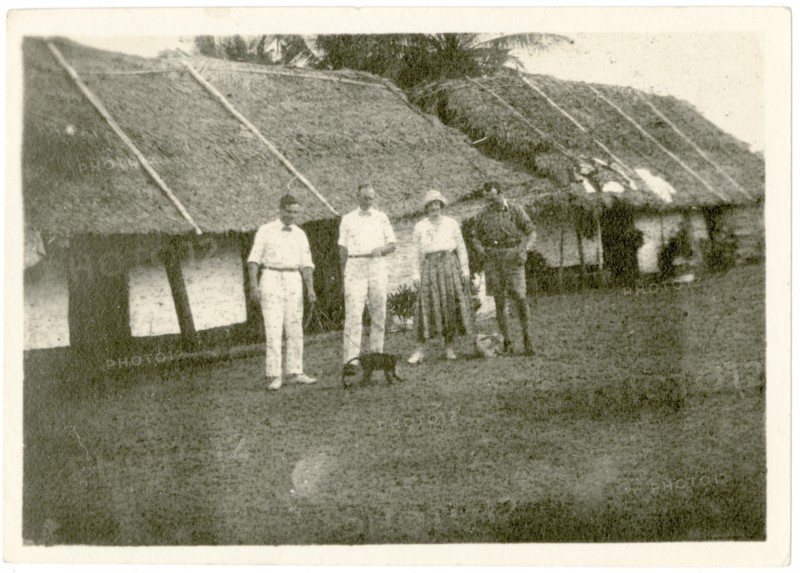 Dorothy Tamlin outside thatched houses