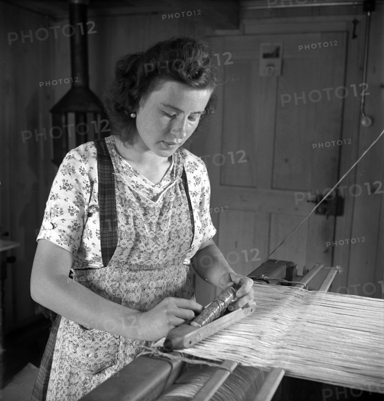 Young woman weaving bast fibre by hand loom, 1946 .