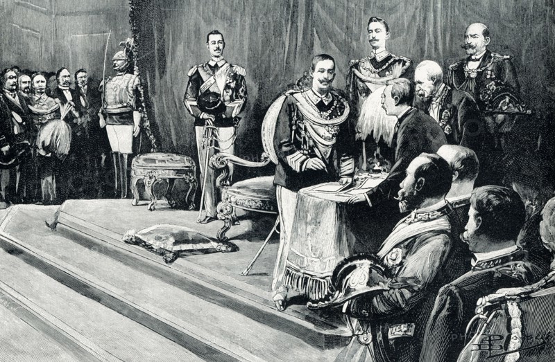 The 1906 caption reads: “Victor Emmanuel III Taking the Oath of Office. Victor Emmanuel III, king of Italy, took the oath of office August 11, 1900. His father had been assassinated nearly two weeks before; but the prince had been at sea in his yacht; and took some time to find him and arrange matters. He signed the oath in the presence of the chief parliamentary officers, judges, and generals of the land, while a brilliant assembly of all Italy’s leading men filled the great hall below the raised dais prepared for the throne.”.