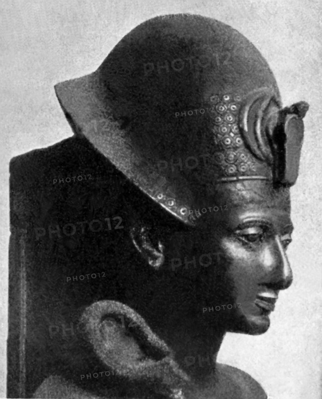 This sculpture is known as the Turin masterpiece portrait of Egypt’s King Ramesses II. In this photon, only the head is shown. The pharaoh appears in the Blue Crown or war helmet, grasping the heqa-sceptre. Contrary to custom, he wears a long full robe that is asymmetrically draped to create an enormous bell sleeve and his feet are shod in sandals. The nose is extremely large, the mouth is proportionally small and the chin is even recessive, all which are unusual until this point. Rameses II is also known as Rameses the Great and he ruled during the 19th Dynasty (New Kindgom) from c. 1279-1213 B.C.