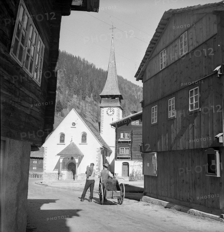 Men with handcart in front of the church; Biel VS; 1946.