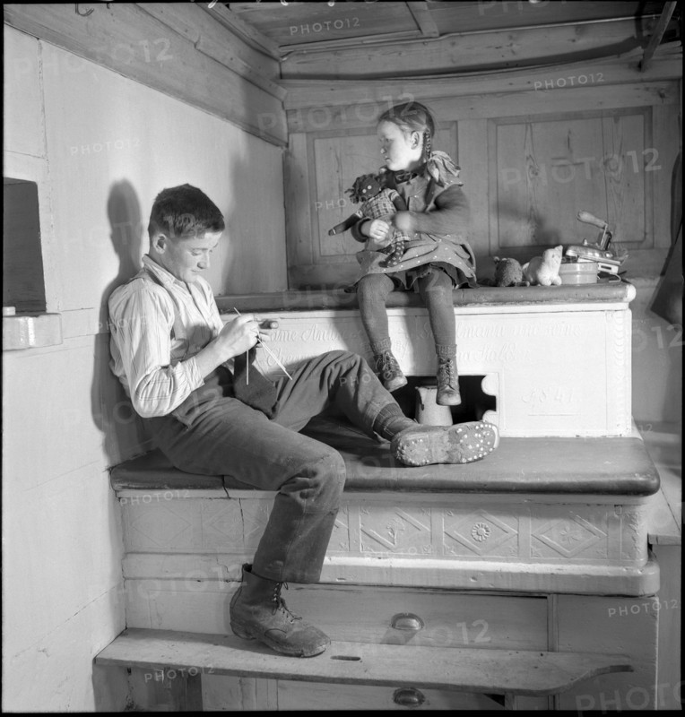 Farmer's children sitting on the tiled stove in 1941.