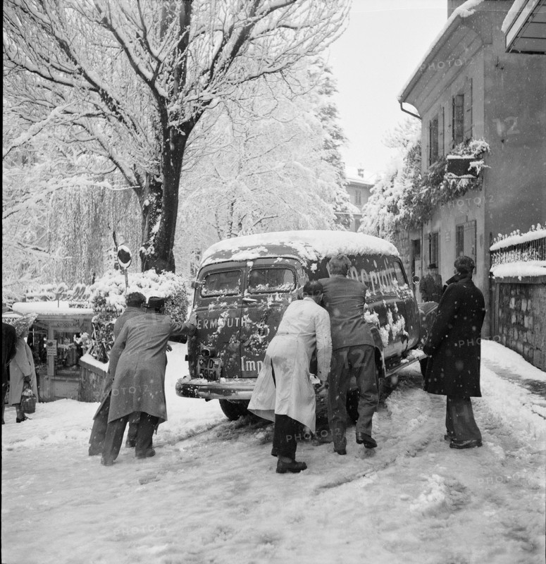 Snowfall in Lausanne: men bump-starting a car; 1952.