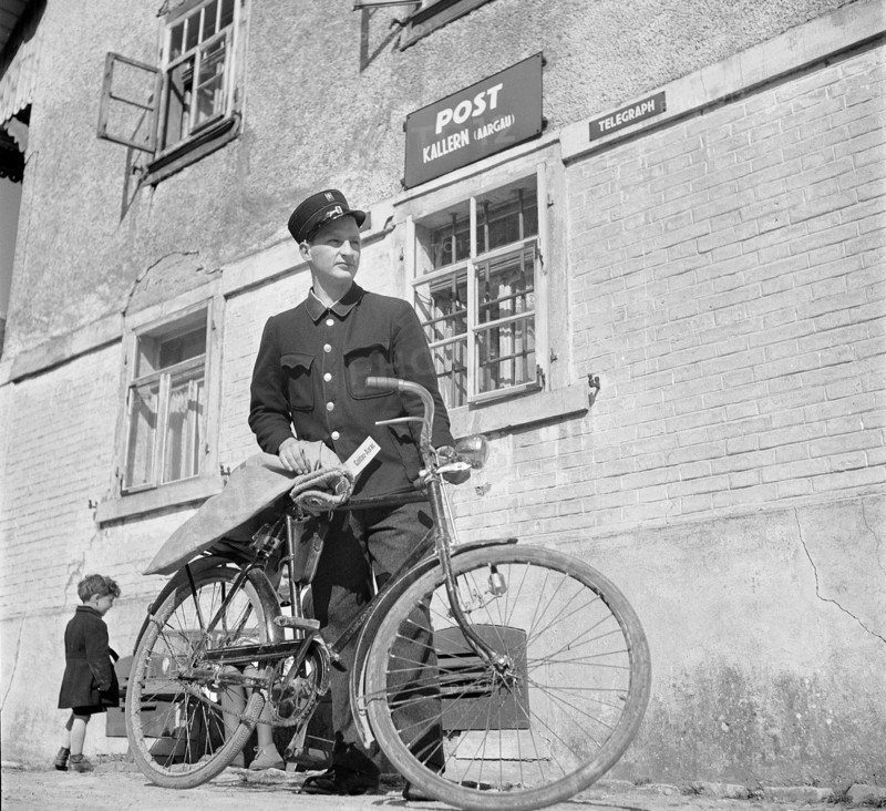 Kallern: poasman with bicycle in front of post office; 1946.