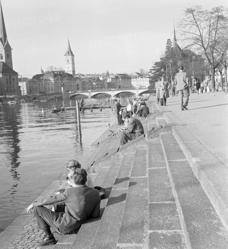 People strolling along the Limmat river.