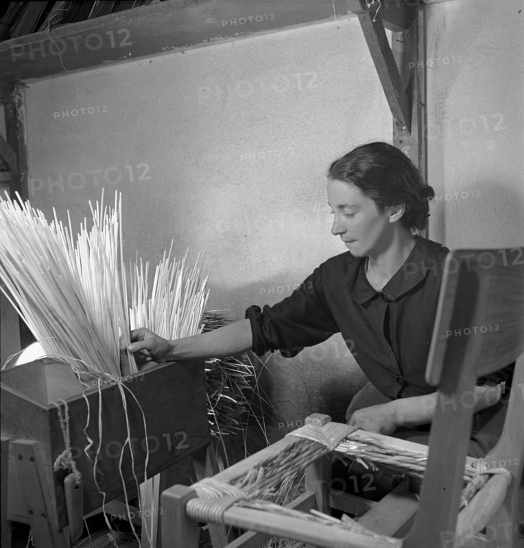 Woman braiding straw around a chair, 1940