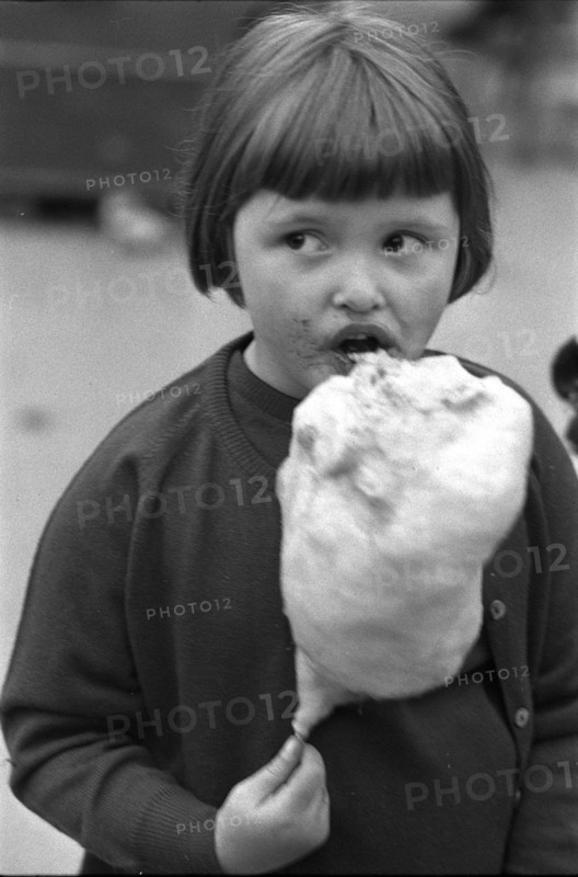 Girl eating cotton candy at fair in Wohlen AG, 1965