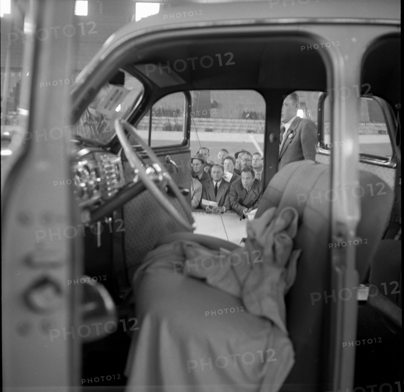 Men watch the auction of a Chrysler; 1955